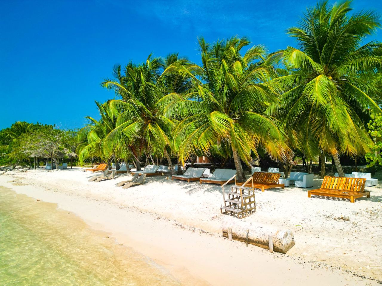 Playa de Barú con palmeras, camas de descanso y mar Caribe cristalino